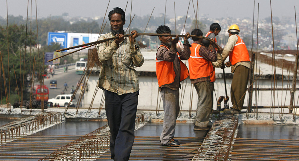 Indian workers carry metal rods on an overpass bridge in Jammu India