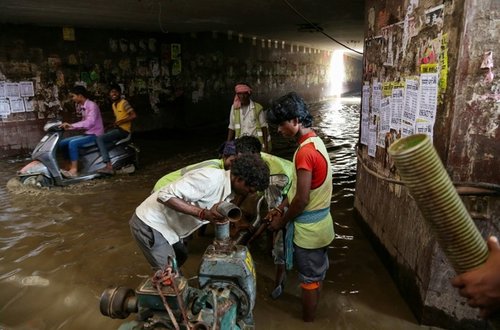 Indian municipal cooperation workers set up a motor to pump water from a flooded subway in Gurgaon