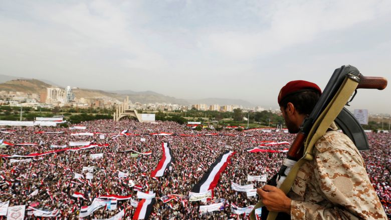 A soldier looks at people rallying to show support to a political council formed by the Houthi movement and the General People's Congress party to unilaterally rule Yemen by both groups in the capital Sanaa