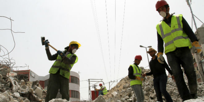 Palestinian workers re-build the commercial center which was destroyed by Israeli shelling during operation protective edge in Rafah in the southern Gaza Strip