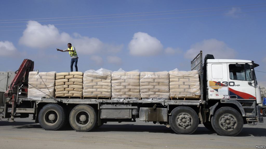 FILE- A Palestinian worker stands atop a truck loaded with bags of cement after entering Gaza at the Kerem Shalom crossing in Rafah in the southern Gaza Strip Nov. 10 2014