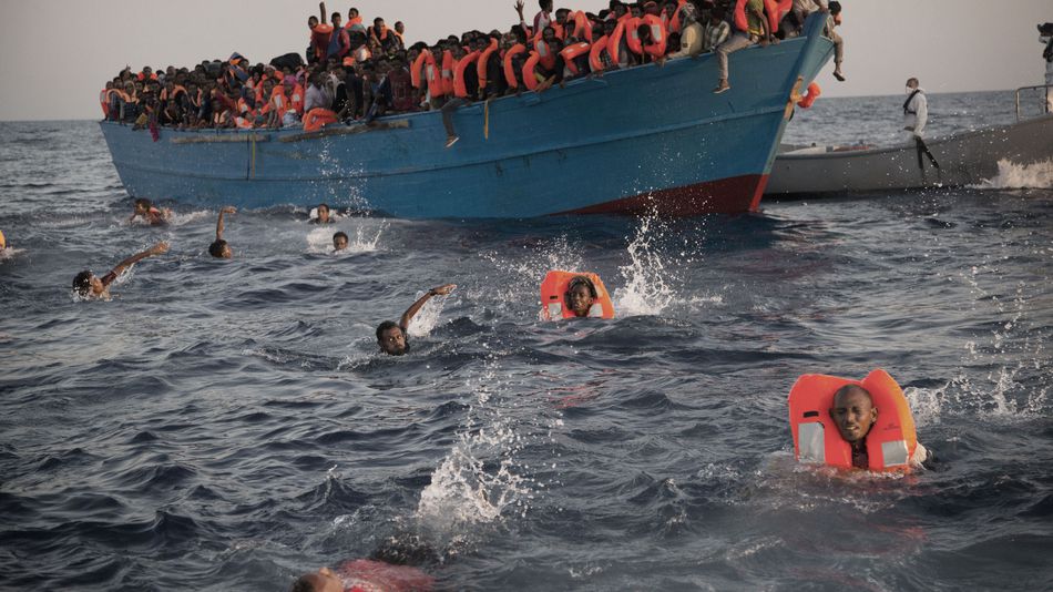 Migrants most of them from Eritrea jump into the water from a crowded wooden boat as they are helped by members of an NGO during a rescue operation in the Mediterranean Sea on Monday