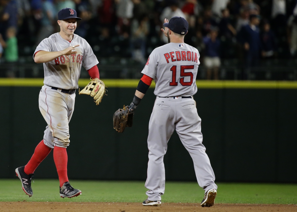 Boston Red Sox outfielder Brock Holt left greets second baseman Dustin Pedroia at the end of a baseball game against the Seattle Mariners Thursday Aug. 4 2016 in Seattle. The Red Sox beat the Mariners 3-2 in 11 innings