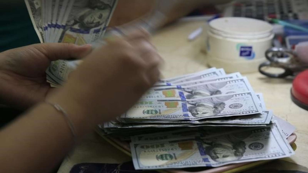 A worker counts U.S. 100-dollar banknotes inside a money changer in Manila Philippines