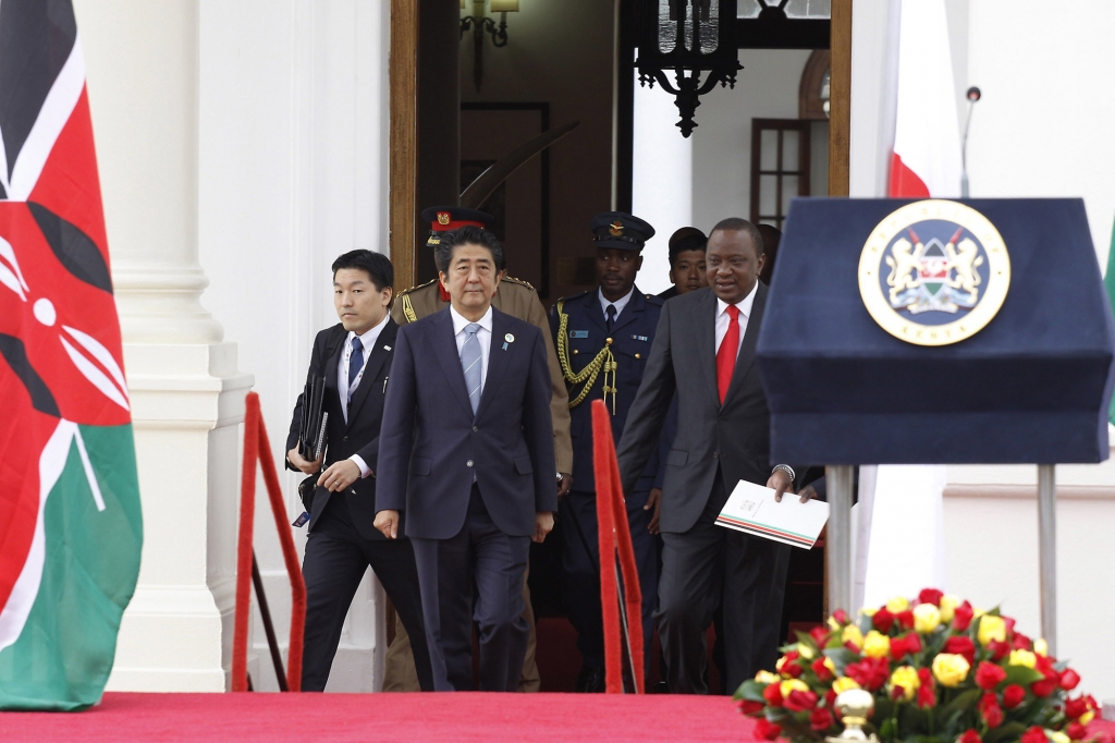 Japan's Prime Minister Shinzo Abe centre and Kenyan President Uhuru Kenyatta right walk together to present a joint press conference outside State House in Nairobi. Kenya Friday Aug. 26 2016. Abe is in Kenya for an official visit. (AP