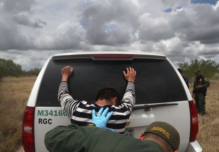 John Moore 
 

 
Detained immigrants are searched after being captured by U.S. Border Patrol agents on Aug. 16 in Roma