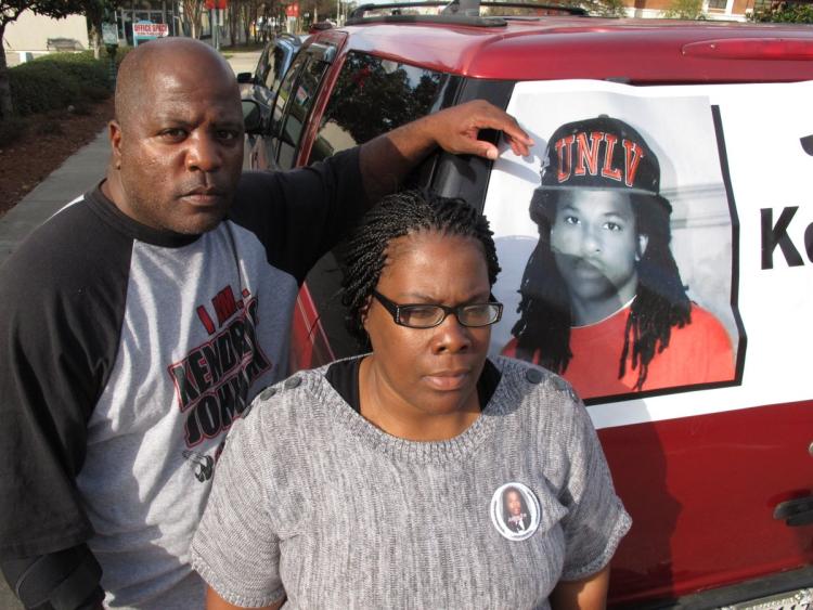 Kenneth and Jacquelyn Johnson stand next to a banner on their SUV showing their late son Kendrick Johnson