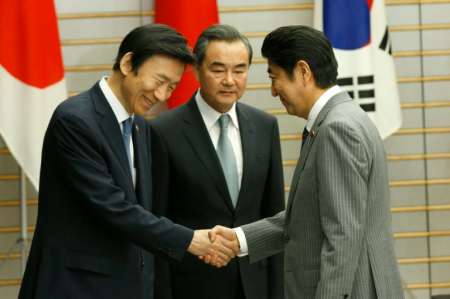 Japanese Prime Minister Shinzo Abe greets South Korean Foreign Minister Yun Byung Se and Chinese Foreign Minister Wang Yi during their meeting in Tokyo