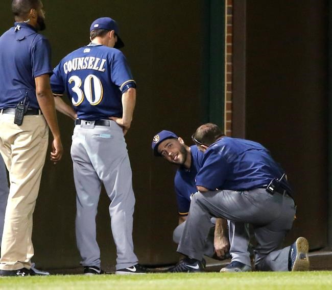 Milwaukee Brewers&#39 Ryan Braun center is checked a member off the Brewers&#39 medical staff and manager Craig Counsell after Braun injured his left leg chasing a foul ball by Chicago Cubs&#39 Ben Zobrist during the fourth inning of the second game