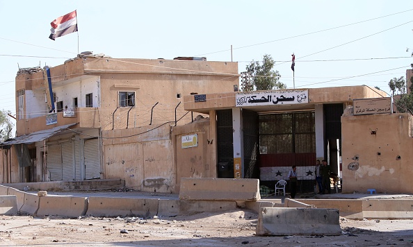 Members of the Syrian regime forces stand at the entrance of a detention centre in the northeastern Syrian city of Hasakeh's Ghweran neighborhood