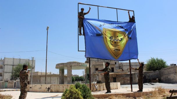 Kurdish-led Syria Democratic Forces raise their flag in the center of the town of Manbij after driving ISIS out of the area Syria