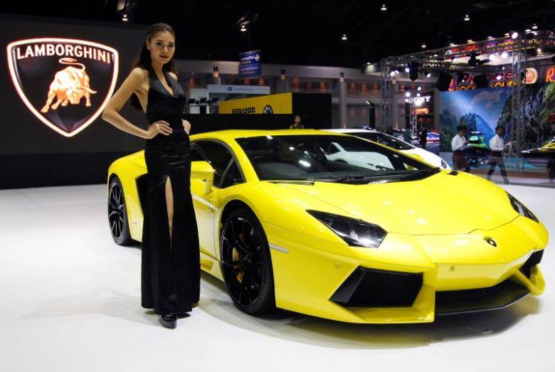 A model poses beside a Lamborghini Aventador LP700-4 during a media presentation at the 37th Bangkok International Motor Show in Bangkok