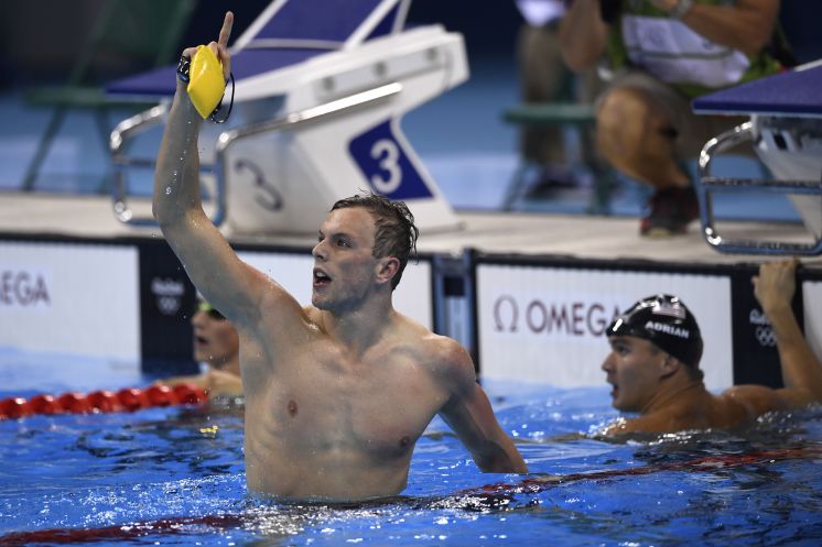 Australia’s Kyle Chalmers punctuates his win in the men’s 100-meter freestyle as American Nathan Adrian right the defending champ looks at the results