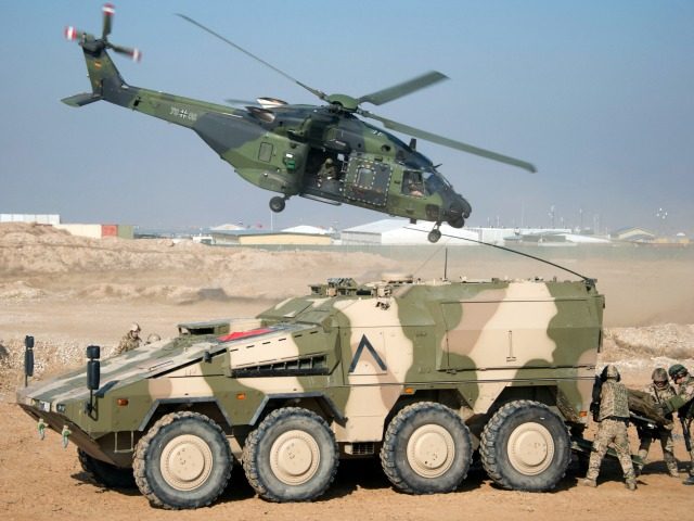 A German Bundeswehr NH90 helicopter flies past a Boxer armoured fighting vehicle during a show of German soldiers at Camp Marmalin Mazar-e Sharif