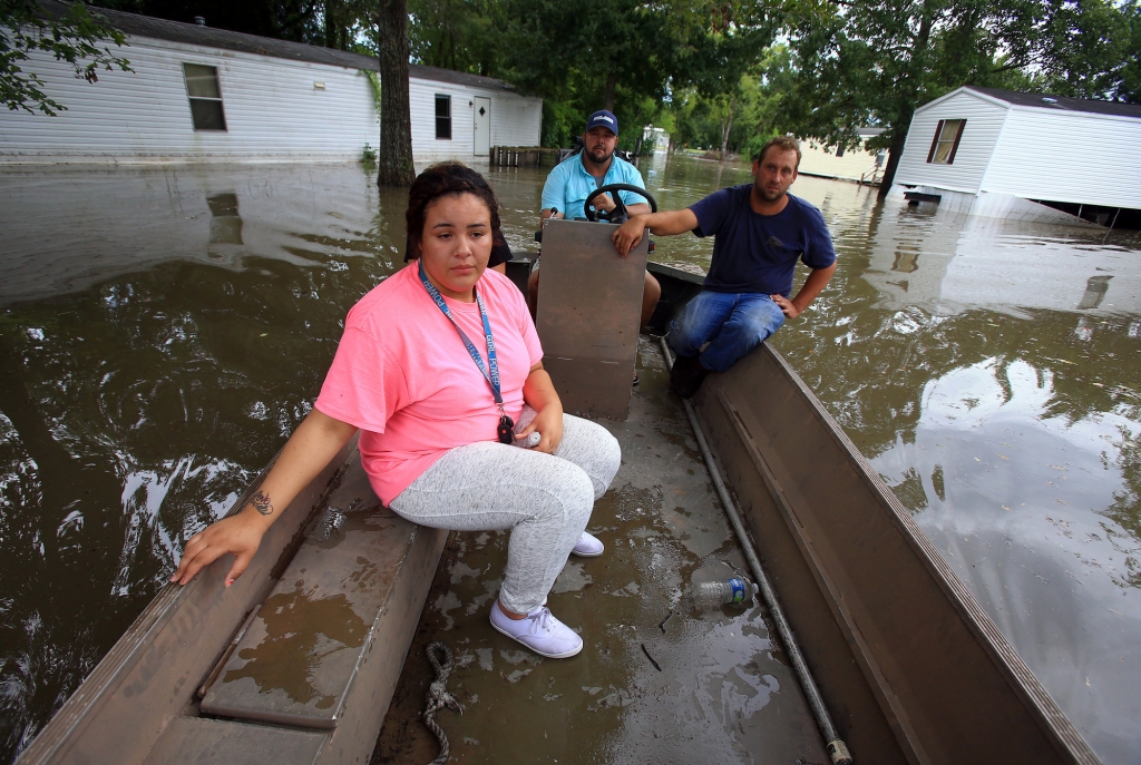 Jasmine Fontenot front gets a boat ride to her home with the help of Darius Girouard back and Fabian Le Blanc after her family was evacuated do to high water from recent rain Tuesday Aug. 16 2016 in Abbeville La. (Gabe Hernandez  Corpus Christi Calle