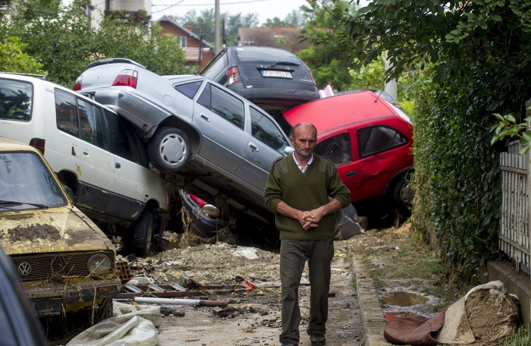 A man passes damaged vehicles in the village of Stajkovci near Skopje