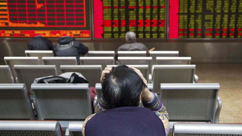 An investor sits in front of an electronic board showing stock information at a brokerage house in Beijing China