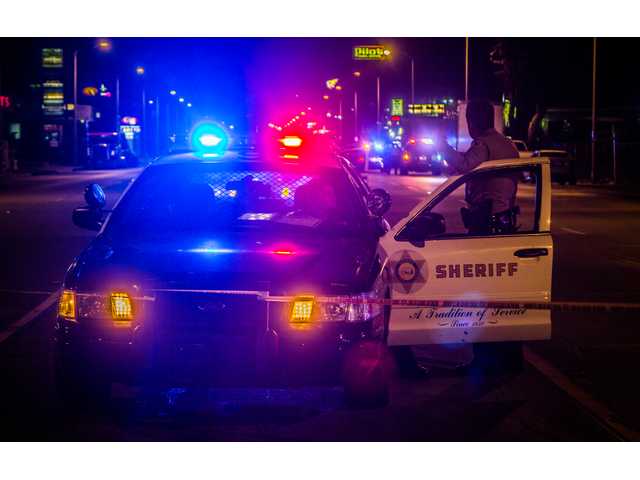 A Santa Clarita Valley Sheriff's Station deputy stands guard outside of a patrol car as homicide detectives process the scene of a deputy-involved shooting in Castaic Tuesday night. Austin Dave  The Signal