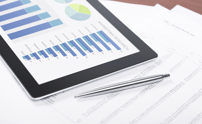 Modern workplace with digital tablet showing charts and diagram on screen pen and paper with numbers