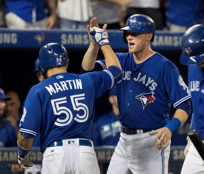 Toronto Blue Jays Russell Martin high-fives with teammate Michael Saunders after he hit a three-run home run against the Houston Astros in the sixth inning of their American League baseball game in Toronto Saturday