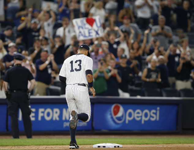 Fans applaud and hold signs as New York Yankees Alex Rodriguez takes his position at third base in the ninth inning of his final game as a Yankee player