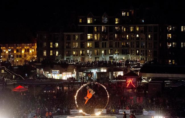 A snowboarder jumps through a ring of fire during a Fire and Ice performance on Whistler Mountain in Whistler B.C. Sunday Jan. 12 2014. Whistler Blackcomb Holdings _ owner of one of Canada's biggest ski resorts _ will be purchased by Colorado-based