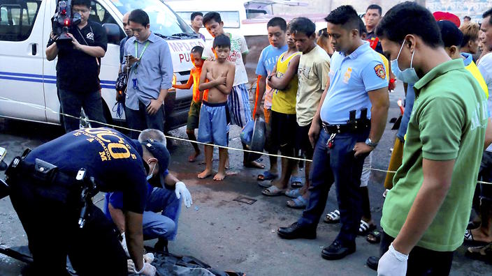 Members of the Philippine National Police examine the scene of a crime where an alleged drug dealer was summarily executed in Manila