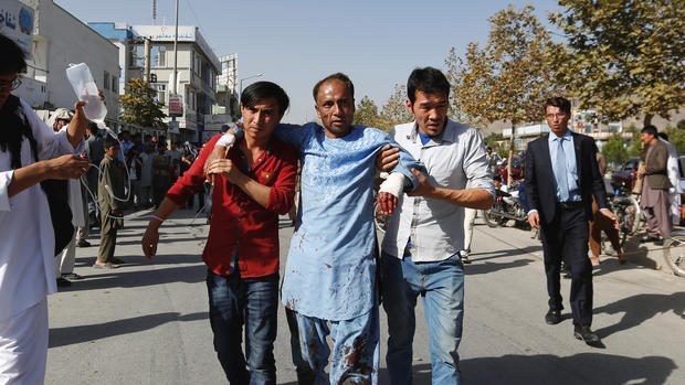 Men help an injured man outside a hospital after a suicide attack in Kabul Afghanistan