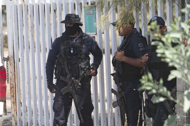 Mexican state police stand guard near the entrance of Rancho del Sol where a shootout with the authorities and susp