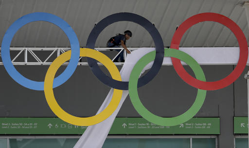 A worker covers the scaffolding holding the Olympic Rings at the Olympic Park ahead of the 2016 Summer Olympics in Rio de Janeiro Brazil Thursday Aug. 4 2016. The Games opening ceremony is on Friday