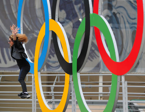 A woman jumps in front of the Olympic rings ahead of the 2016 Summer Olympics in Rio de Janeiro Brazil Wednesday Aug. 3 2016