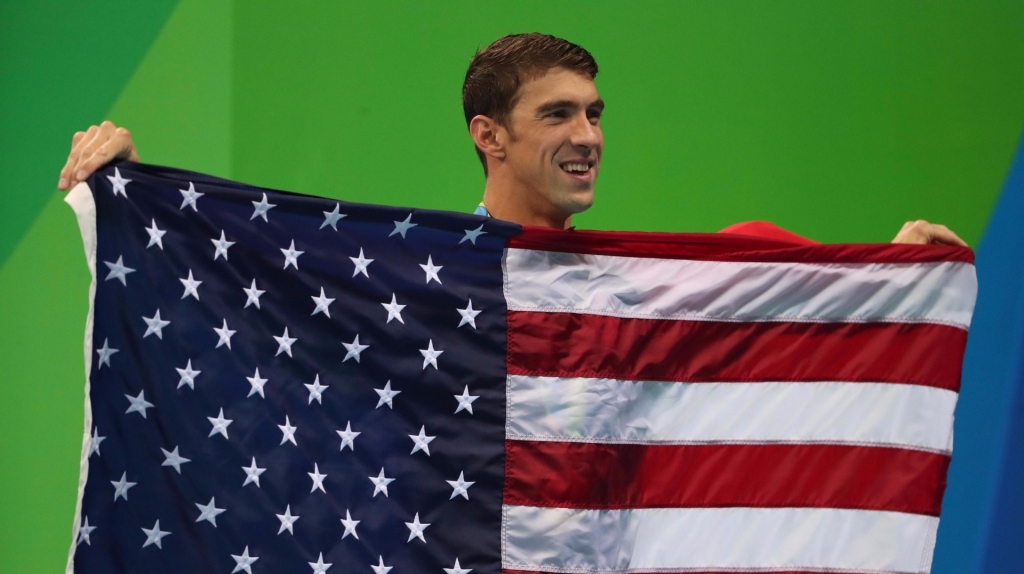 Michael Phelps holds up the U.S. flag after winning his final gold medal