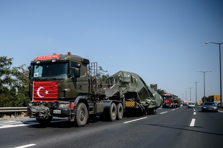 Military trucks with the Turkish national flag transport tanks as they drive on a highway out of Istanbul