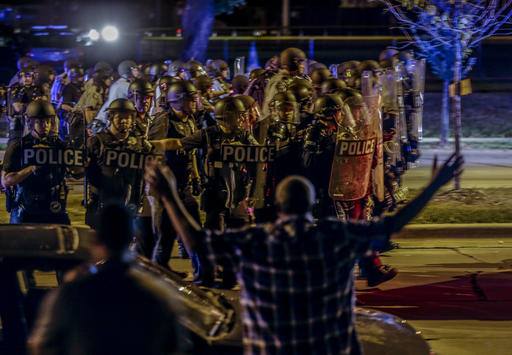 Police move in on a group of protesters throwing rocks at them in Milwaukee Sunday Aug. 14 2016. Police said one person was shot at a Milwaukee protest on Sunday evening and officers used an armored vehicle to retrieve the