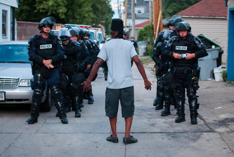 A man talks to police in riot gear as they wait in an alley after a second night of clashes between protestors and police in Milwaukee