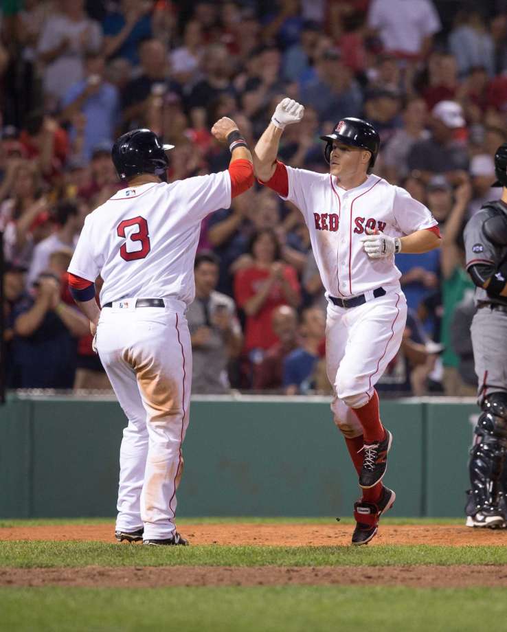 BOSTON MA- AUGUST 13 Brock Holt #12 of the Boston Red Sox celebrates his home run against the Arizona Diamondbacks with teammate Sandy Leon #3 during the sixth inning at Fenway Park