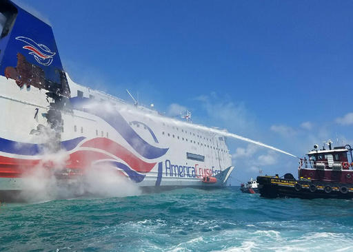 U.S. Coast Guard a local San Juan Puerto Rico-based tug crew uses a fire hose to cool the hull of the Caribbean Fantasy cruise ship that caught fire a mile