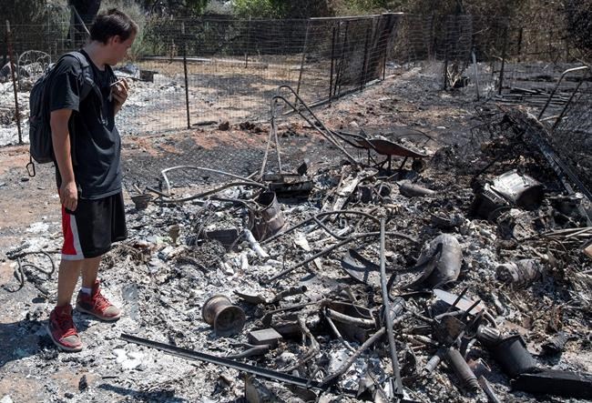 Daniel Brown uses a chat app with his mother while surveying damage to his home after a fire tore through his neighborhood in Lower Lake Calif. Tuesday Aug. 16 2016. People forced to flee a massive wildfire in mountains north of San Francisco heaped