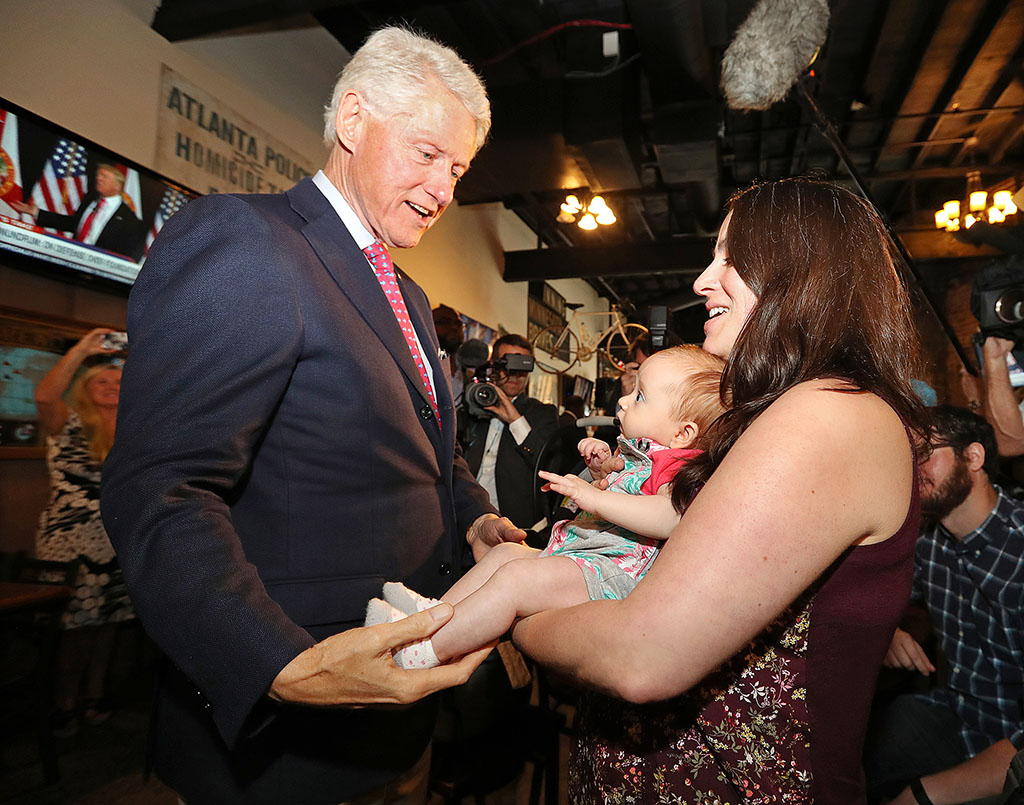 Former President Bill Clinton left says hello to Megan Bartlett of Decatur Ga. and her 3-month-old daughter Hannah Rice as he works the crowd at historic Manuel's Tavern Wednesday Aug. 24 2016 during a stop in Atlanta. (Curtis Compton  Atlanta Jo