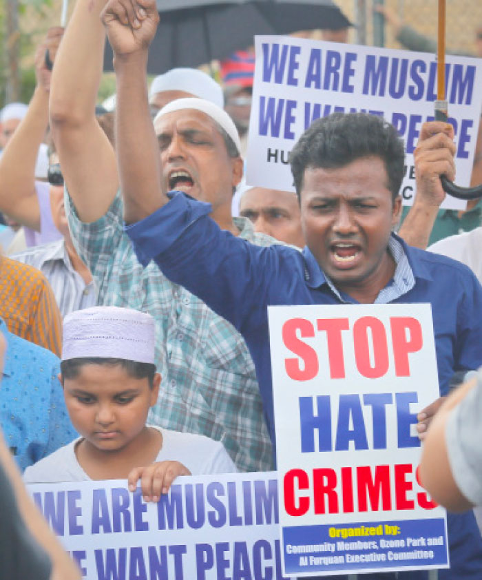 Mourners hold signs protesting the killings of Imam Maulama Akonjee and Thara Uddin during funeral services for both men on Monday. — AP