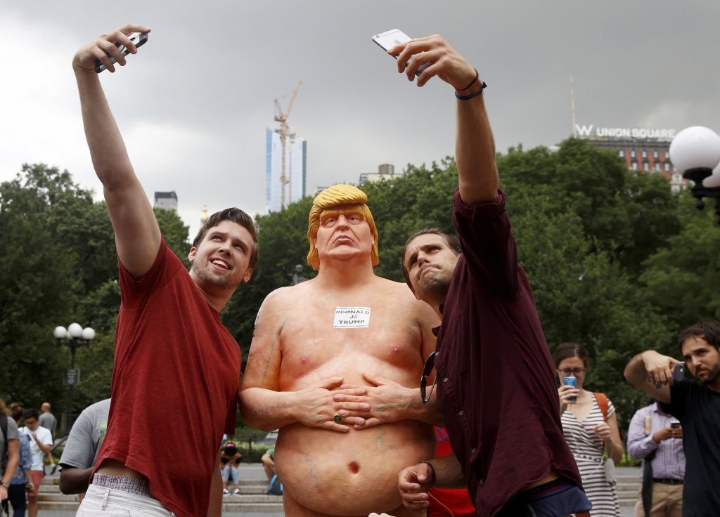 People pose for selfies with a naked statue of U.S. Republican presidential nominee Donald Trump that was left in Union Square Park in New York City on Aug. 18 2016