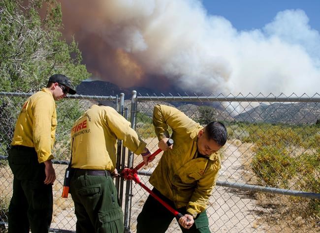 U.S. Forest Service firefighters break a lock on a gate as they prepare to battle a wildfire in Summit Valley Calif. on Sunday