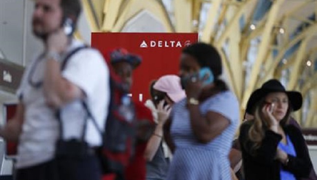 Travelers talk on their cell phones as they stand in line at the Delta ticketing counter at Washington's Ronald Reagan Washington National Airport Monday Aug. 8 2016