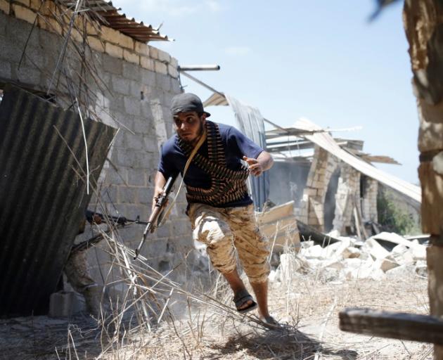 A fighter of Libyan forces allied with the UN-backed government runs for cover during a battle with Islamic State fighters in Sirte at the weekend