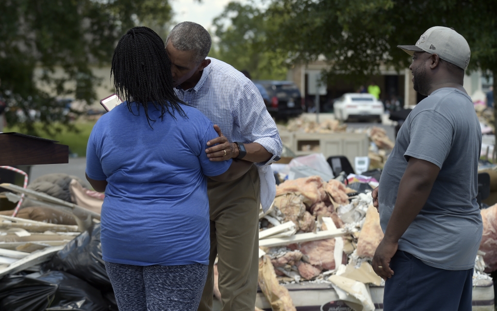 President Barack Obama gives Melissa Williams a kiss as her husband Le Roy Williams watches during Obama's tours of Castle Place a flood-damaged area of Baton Rouge La