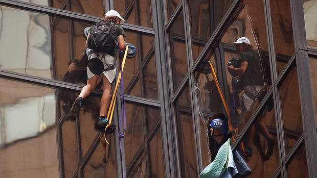 Officers from the NYPD attempt to detain a man as he climbs the outside of Trump Tower Wednesday