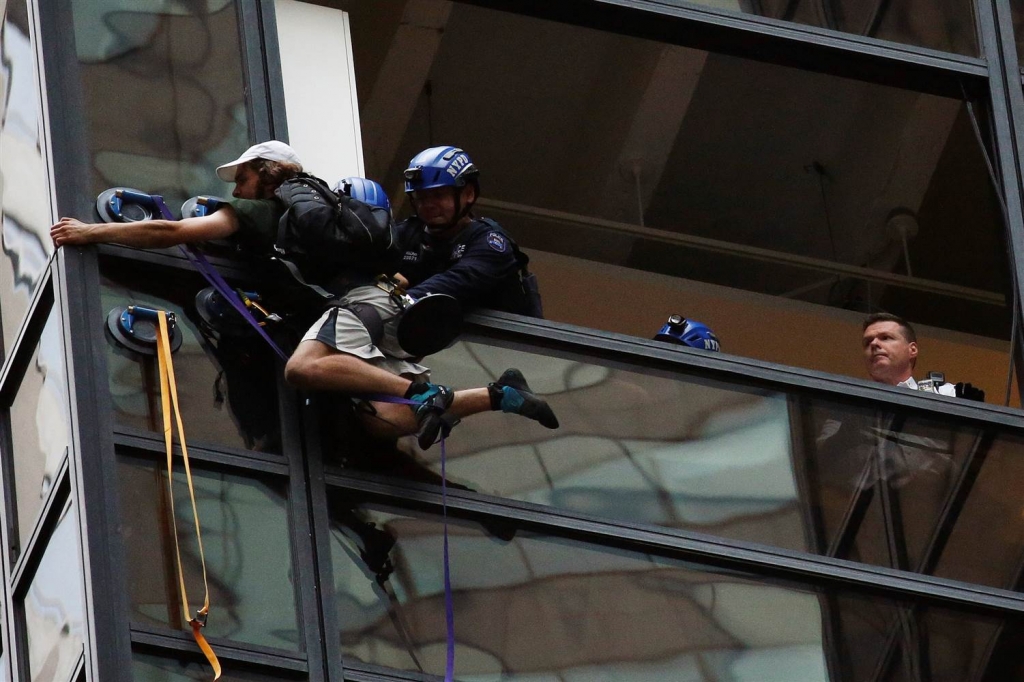 Image Officers from the NYPD embrace a man to stop him from climbing the outside of Trump Tower in New York