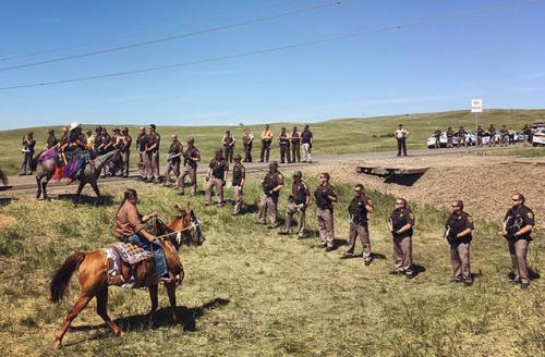 Dakota riders from the Standing Rock and Rosebud reservations push back the police line at the Dakota Access Pipeline construction site