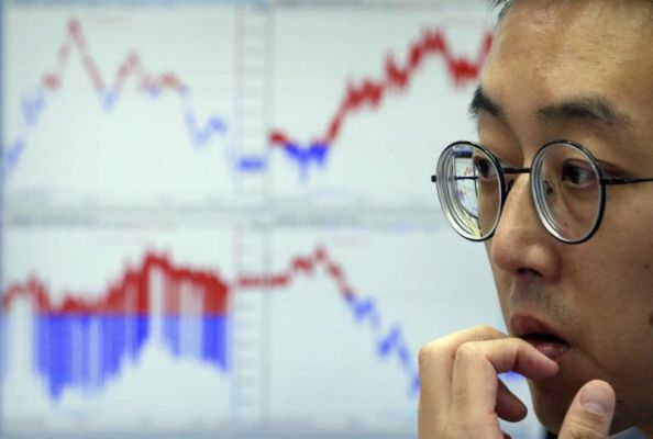 A currency trader watches monitors at the foreign