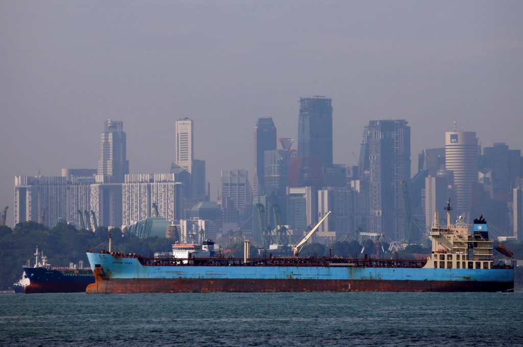 Oil tankers pass the skyline of Singapore